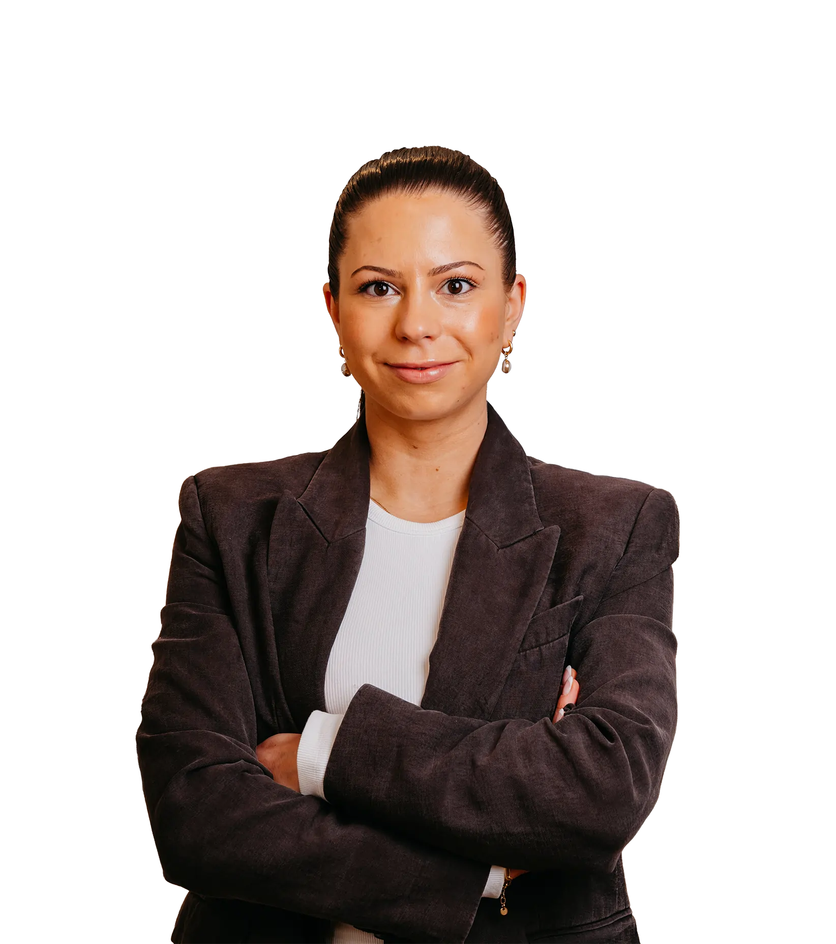 Geschäftsfrau mit zusammengebundenem Haar, die selbstbewusst die Arme verschränkt trägt, bekleidet mit einem dunklen Blazer und weißem Oberteil.