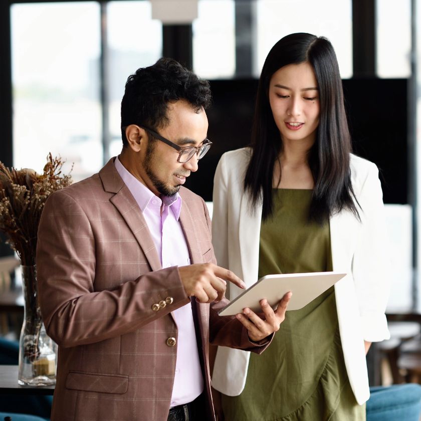 Two people look at a tablet device while having a business discussion.