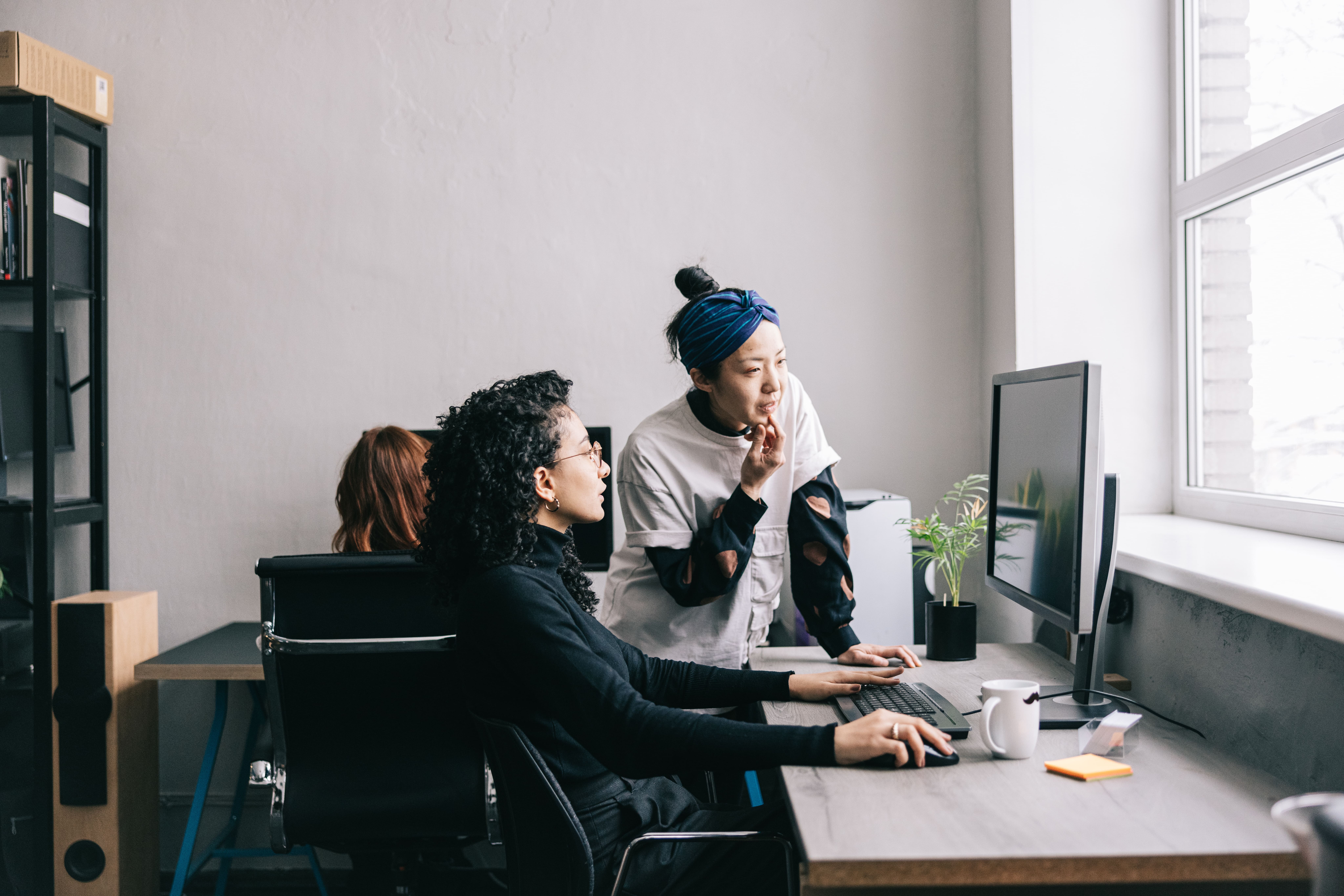 Two professionals on a computer screen in a modern office, illustrating team-based data governance collaboration.