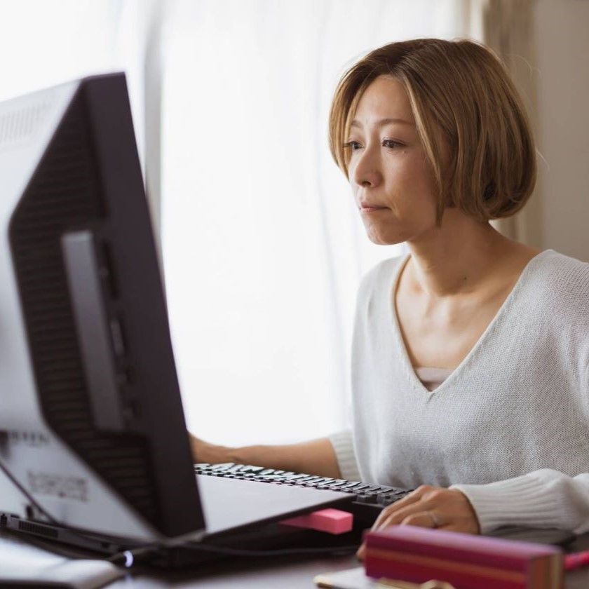 A person in a white sweater uses a desktop monitor, highlighting concentration on searching for work files.