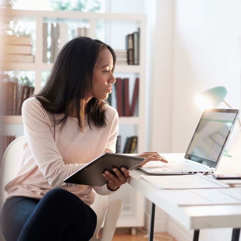 An individual in a home office reviews information across devices, suggesting secure handling of sensitive content.