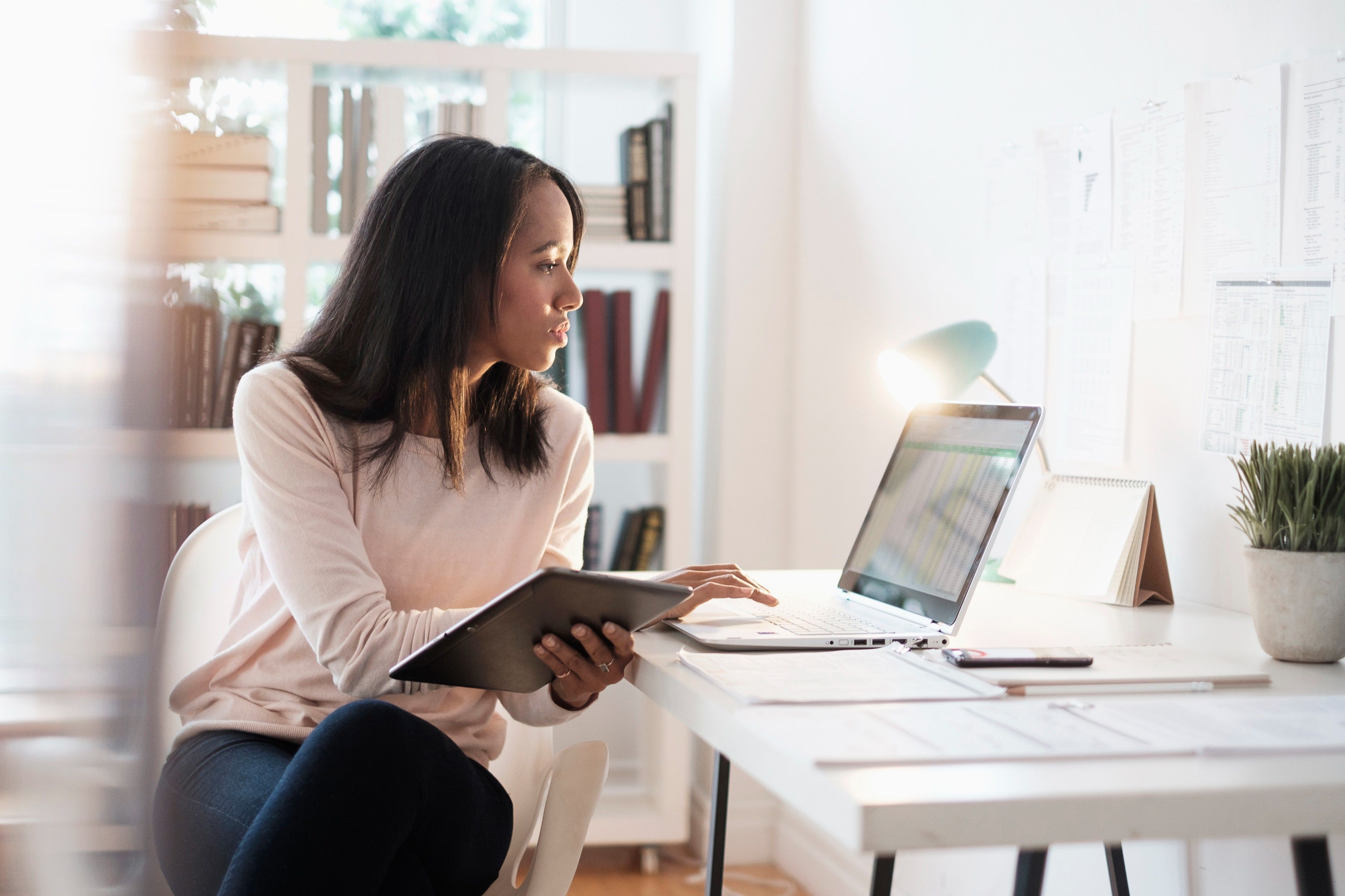 A person works with spreadsheet data on a laptop and tablet, reflecting attention to digital privacy and access controls.