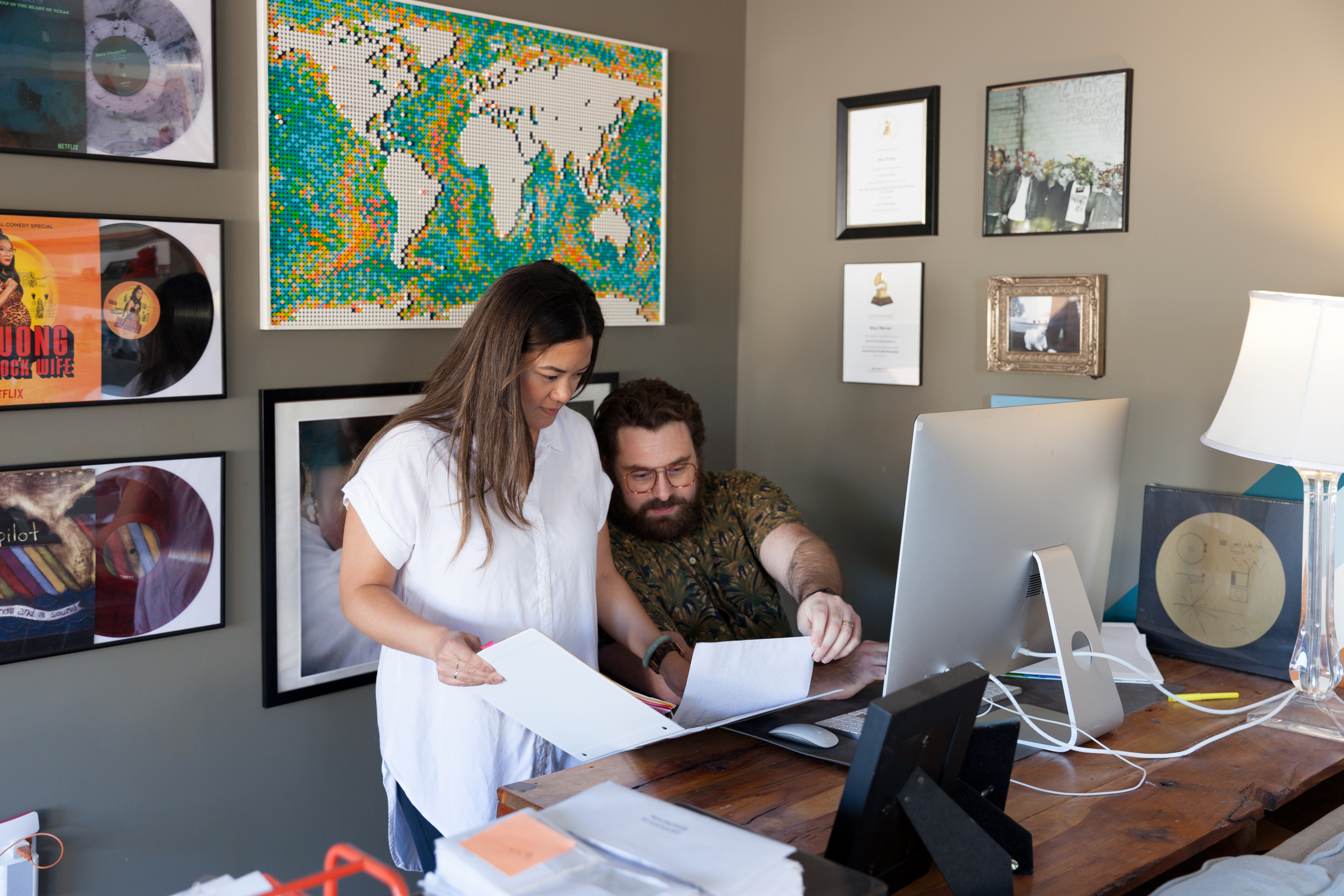 Creative team organizing campaign materials using both paper documents and a computer screen.