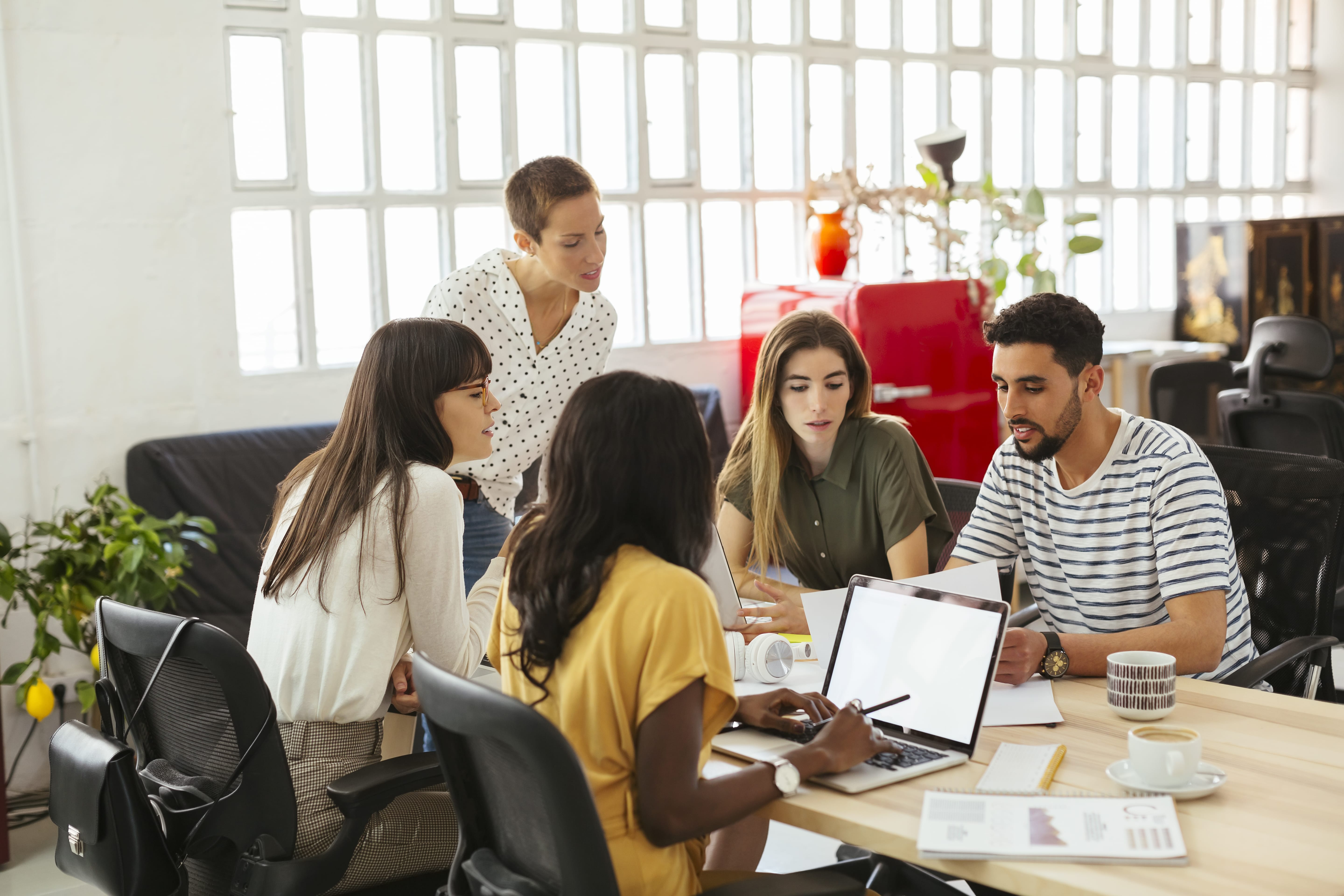 A creative team gathers around a meeting table discussing a project.