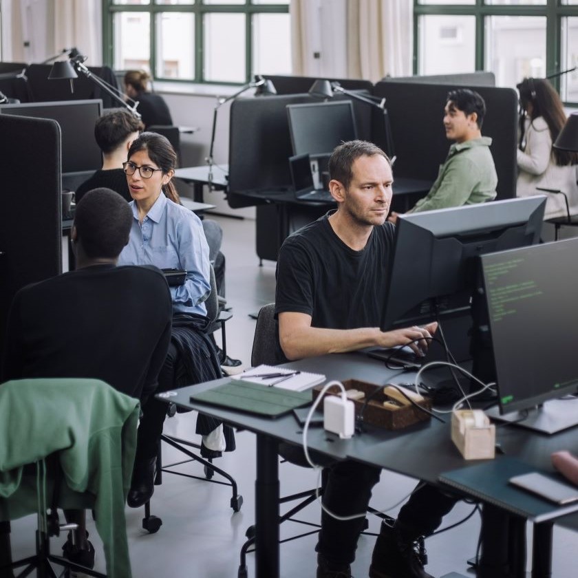 A sales and marketing team working together at desks in an open office, planning a content strategy using AI.