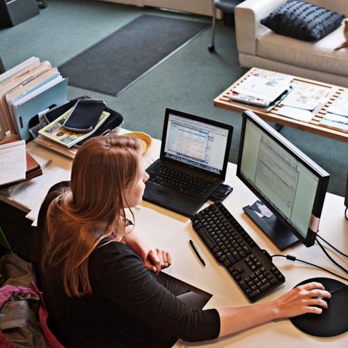 A person sits at their home workstation while analyzing data on their screen.
