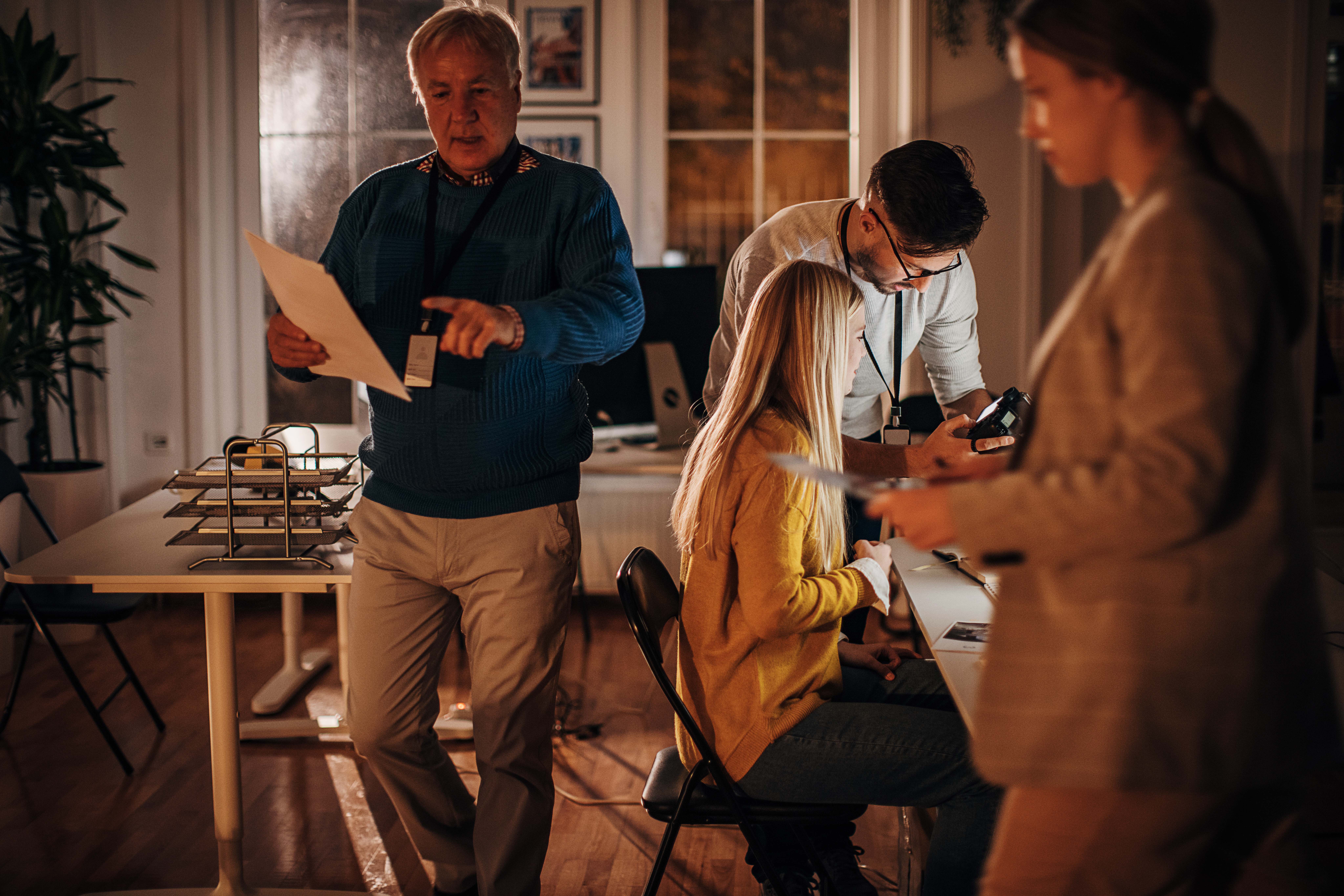 Team prepares creative assets with camera and briefing documents in an office setting, for campaign planning and review.