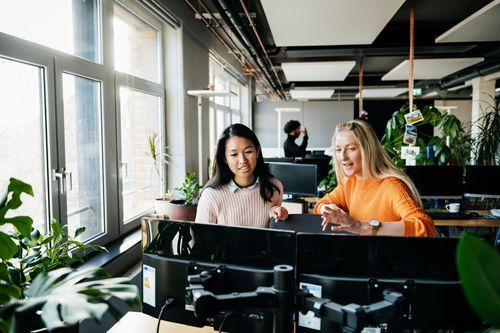 Two people sit at a desk in an office while discussing a campaign.