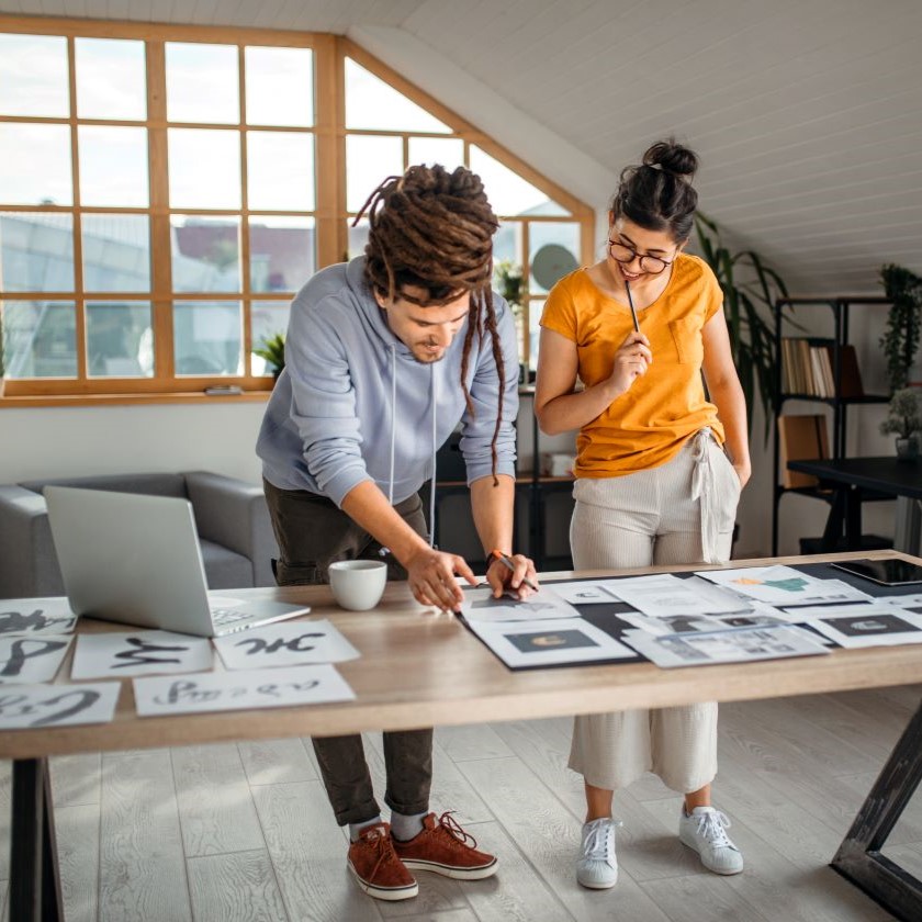 Team collaborates on printed and digital creative assets, reflecting stages of content development and review.