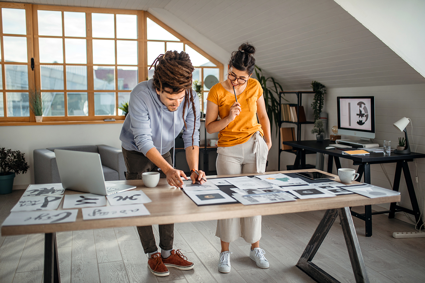 Creative professionals review printed design drafts while collaborating, reflecting stages of content development and review.