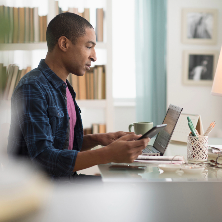 A person sits at their home office desk with a cup of coffee while writing.