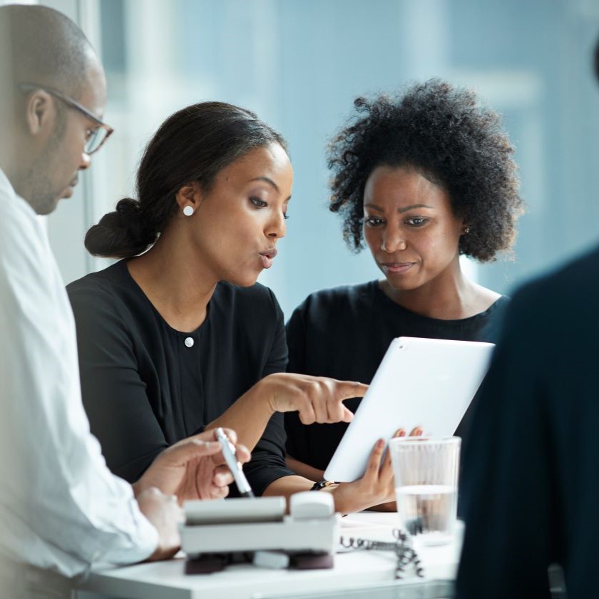 Team reviewing AI-generated meeting notes on a tablet, evaluating accuracy and relevance.