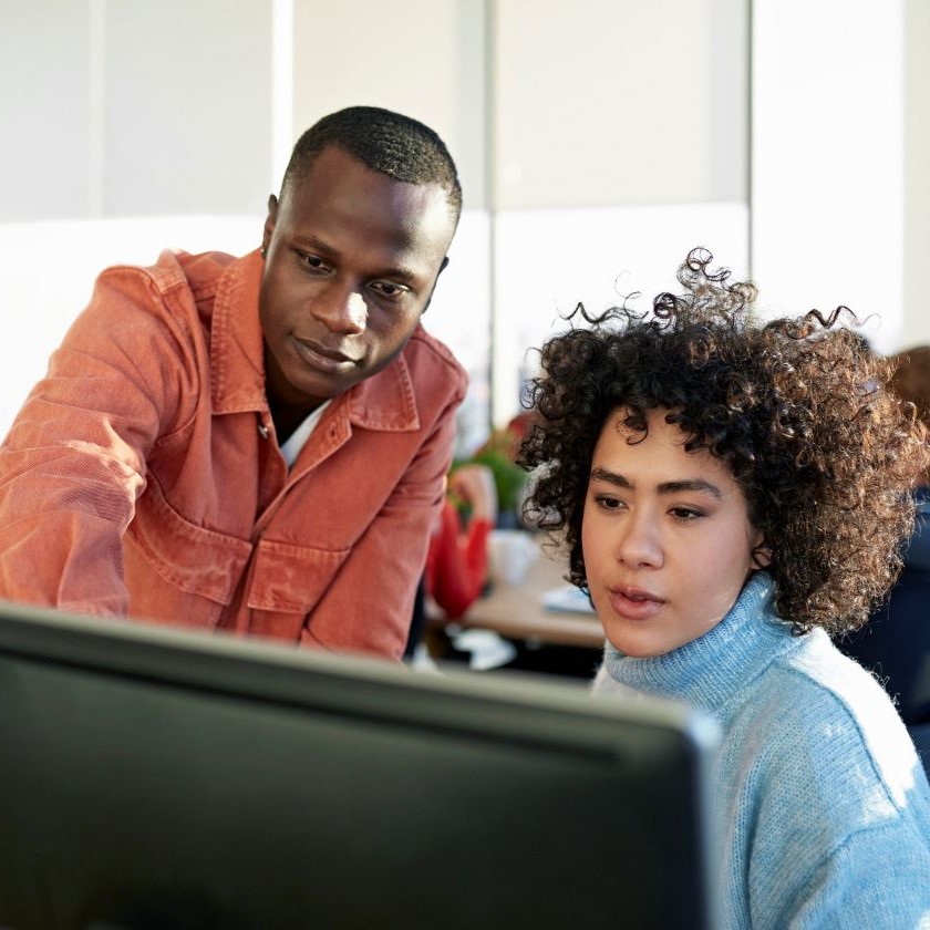 Coworkers review content on a desktop screen together, discussing how to summarize documents with AI.