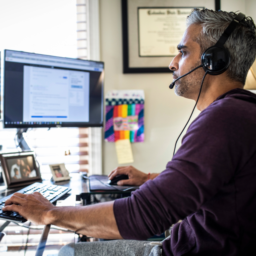 A person sits at their home office desk while concentrating on a task.