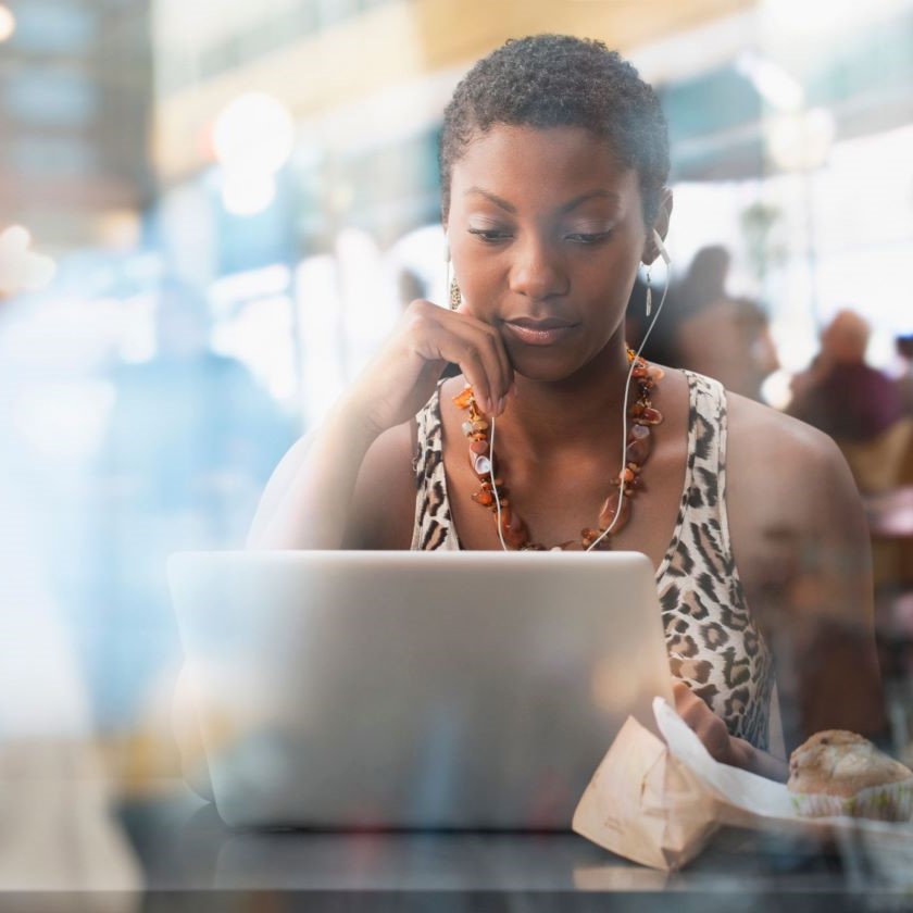 A person sits in a busy cafe while working remotely on their laptop.