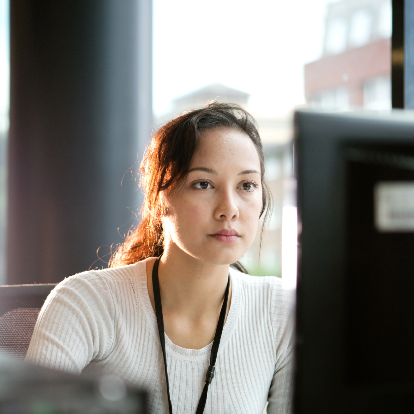A person concentrates on a computer screen at their office desk.