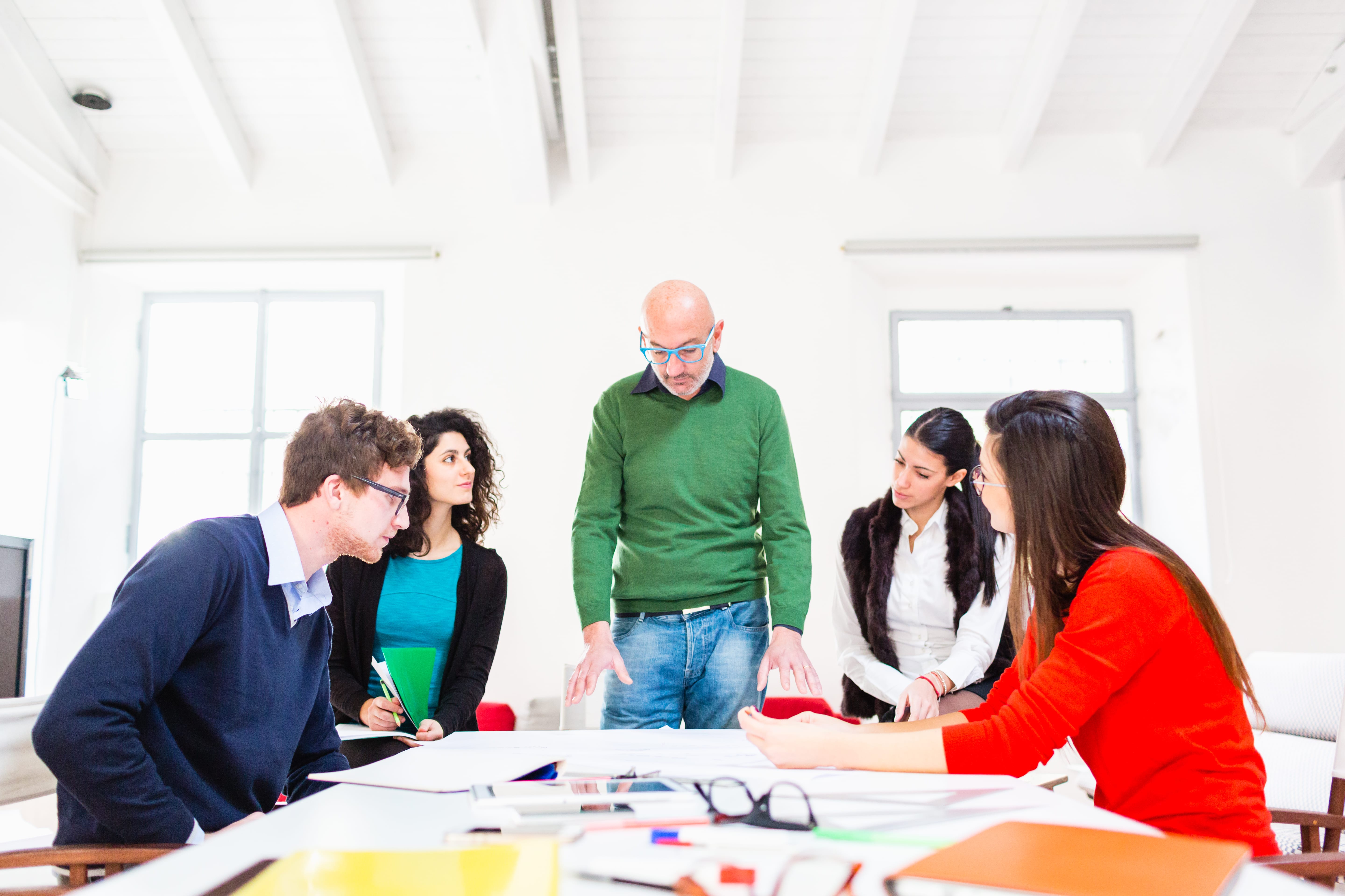 A team gathered around a table reviewing campaign plans, with leader presenting key points.