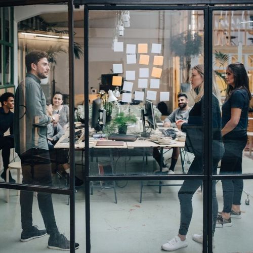 A group of colleagues have an ideas session while gathered in an open-plan office space.