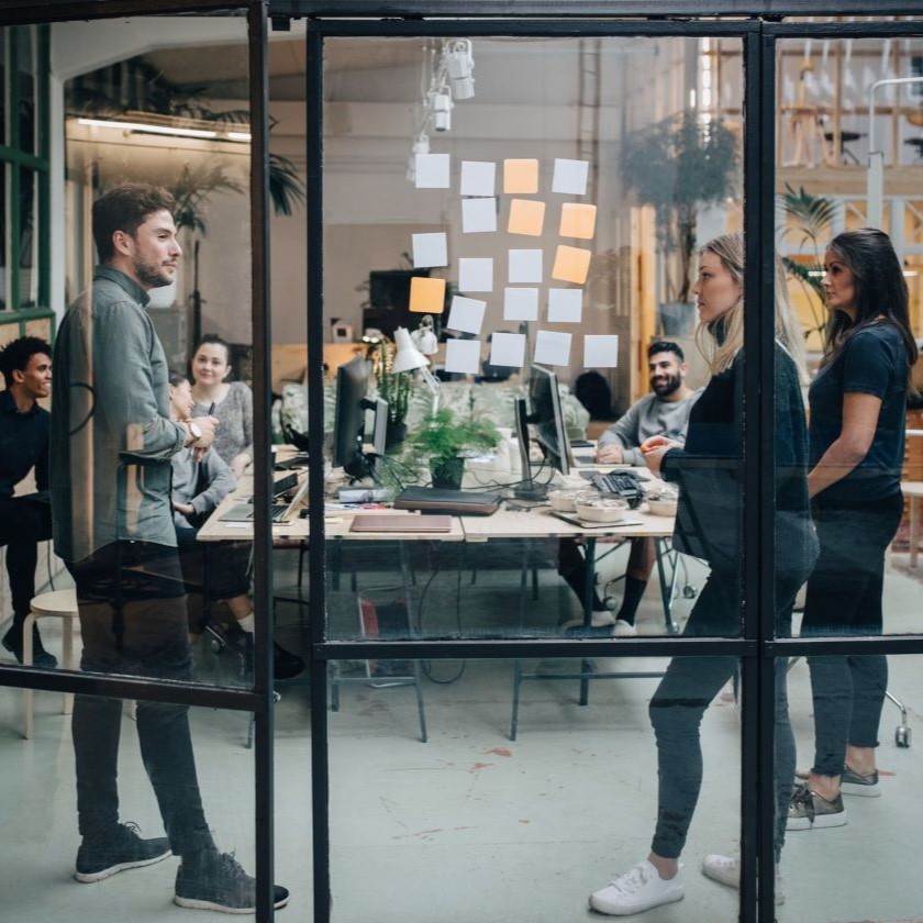 A group of colleagues have an ideas session while gathered in an open-plan office space.
