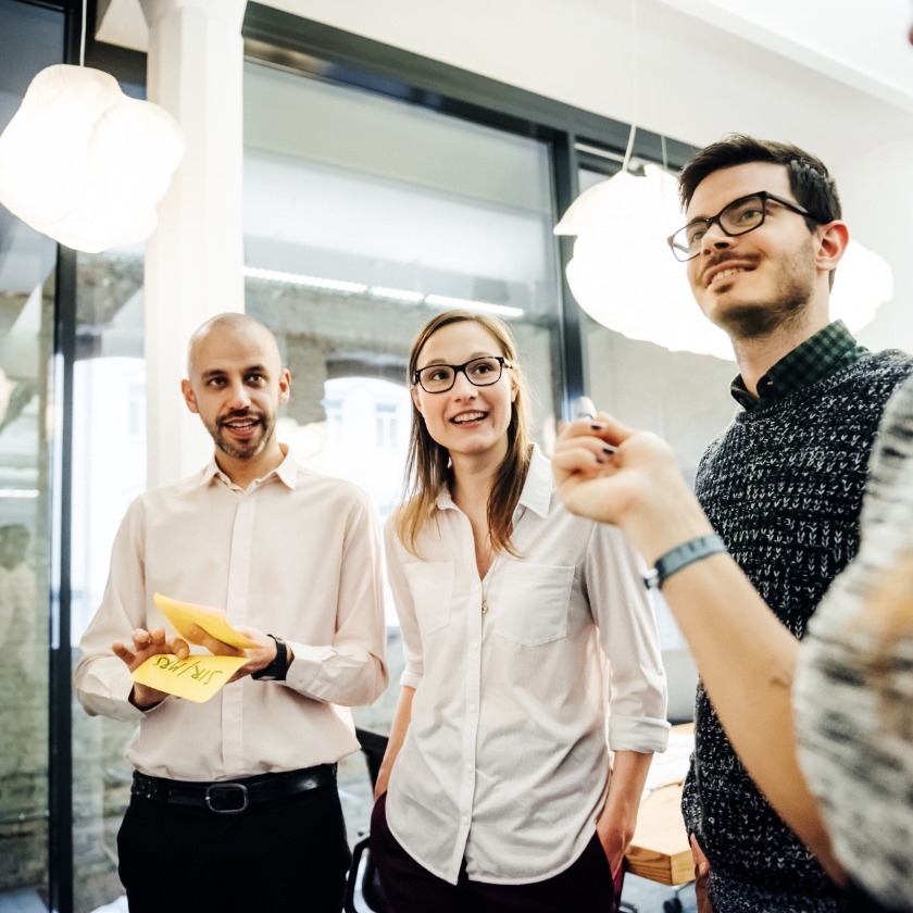 A group of colleagues brainstorming together using sticky notes on a whiteboard.