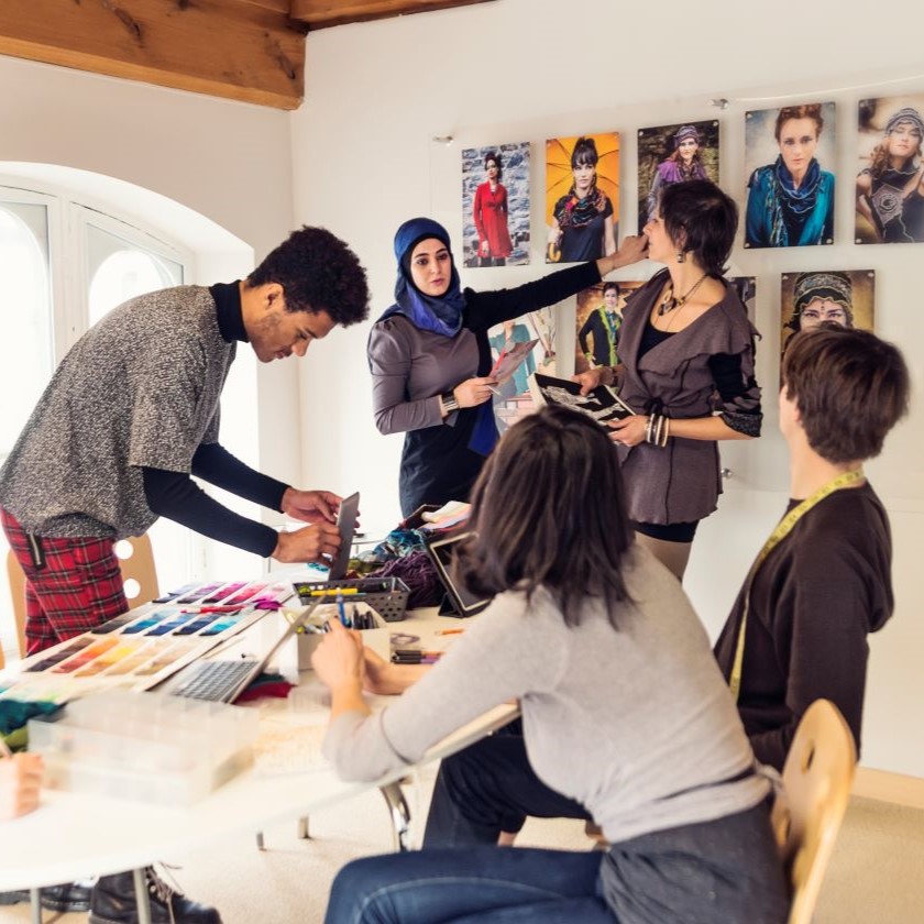 Group of marketers and creatives reviewing campaign visuals and color palettes in a workspace with collaborative tools.