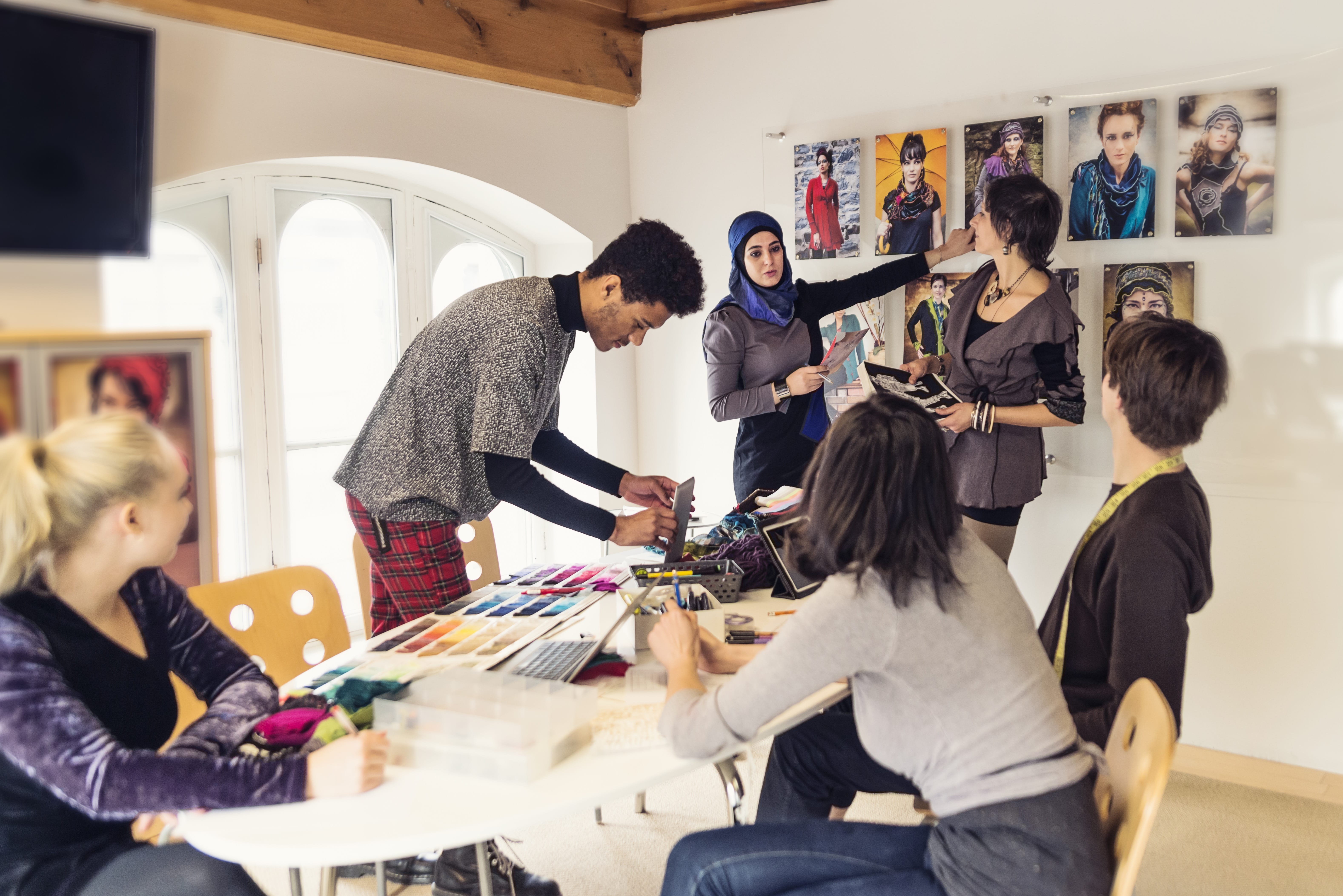 Group of marketers and creatives reviewing campaign visuals and color palettes in a workspace with collaborative tools.