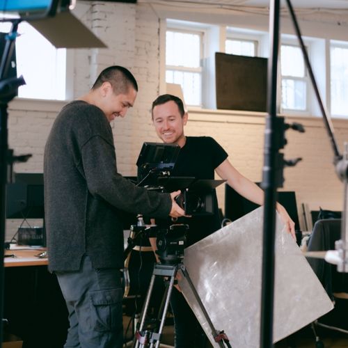 Creative team members reviewing captured video on camera equipment in a well-lit production studio.