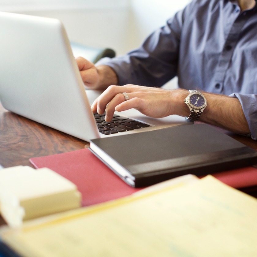 A person sits concentrating at their home desk while working on a laptop.