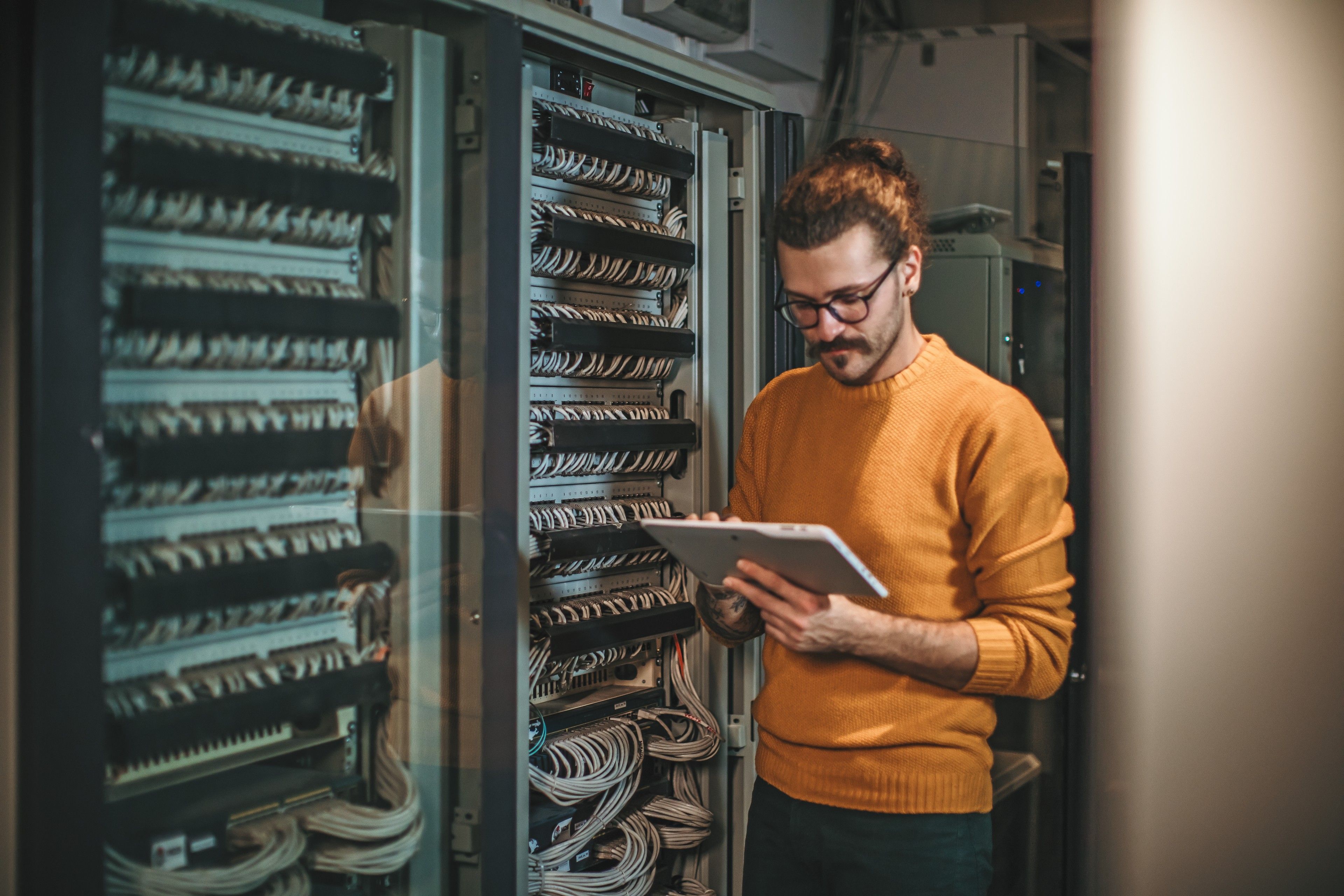 A person attends to a task while standing in a large data center and working on their tablet device.