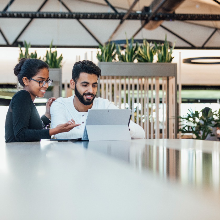 Two colleagues reviewing a document together on a tablet in a modern office setting.