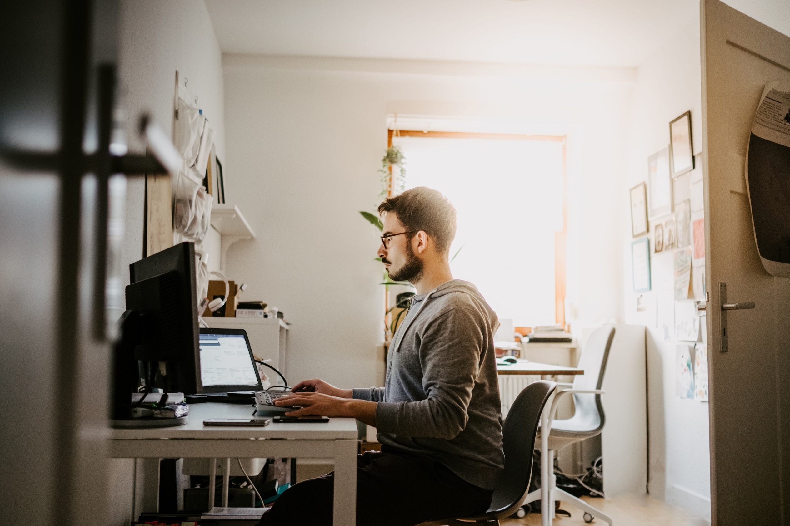 Person in a home office managing documents on a desktop computer with organized desk setup.