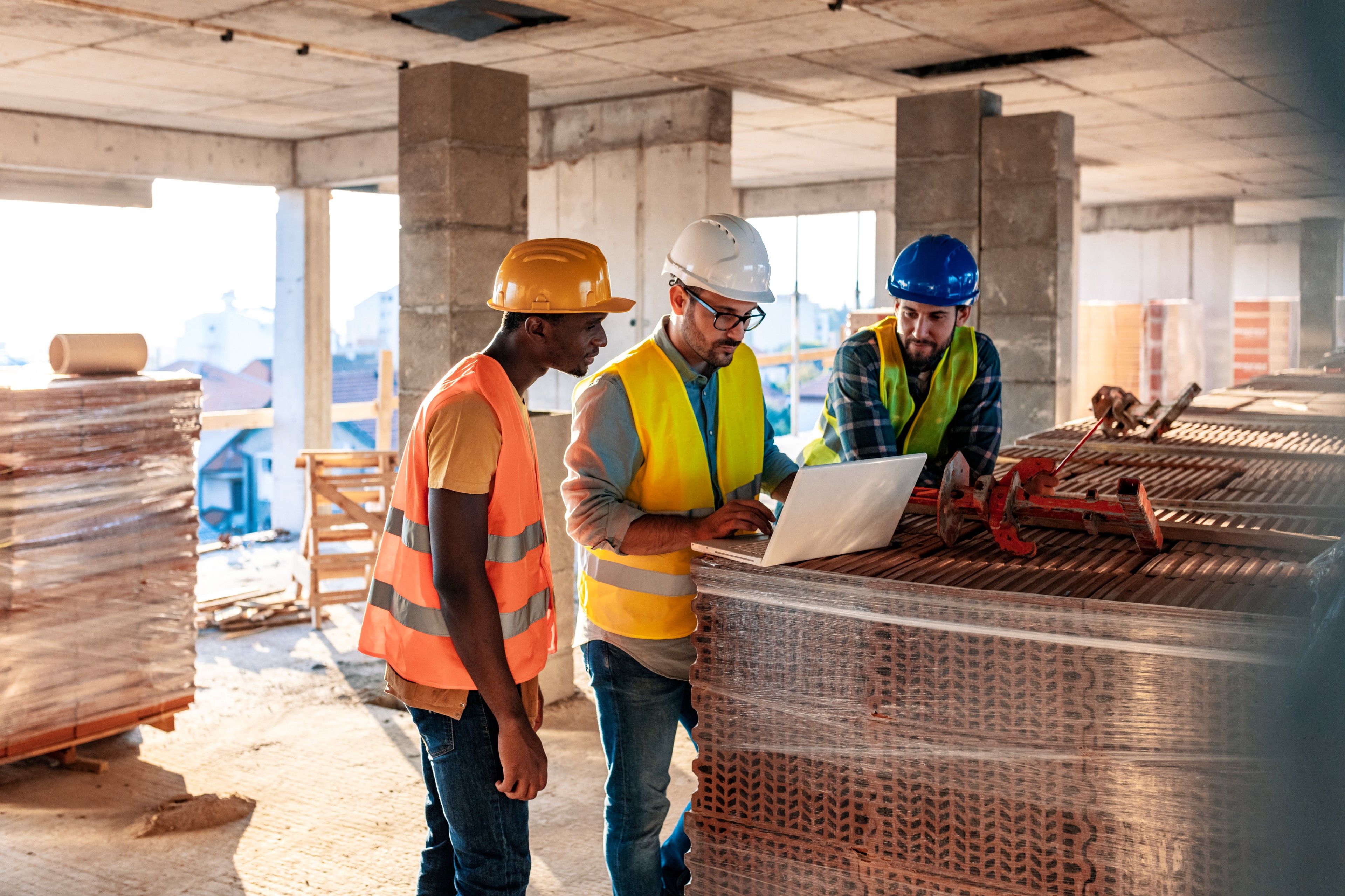 People gather on a construction site surrounded by materials while having a discussion.