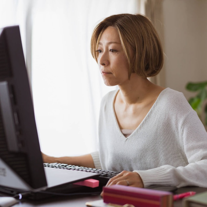 A person sits at their computer at home while concentrating on a task.