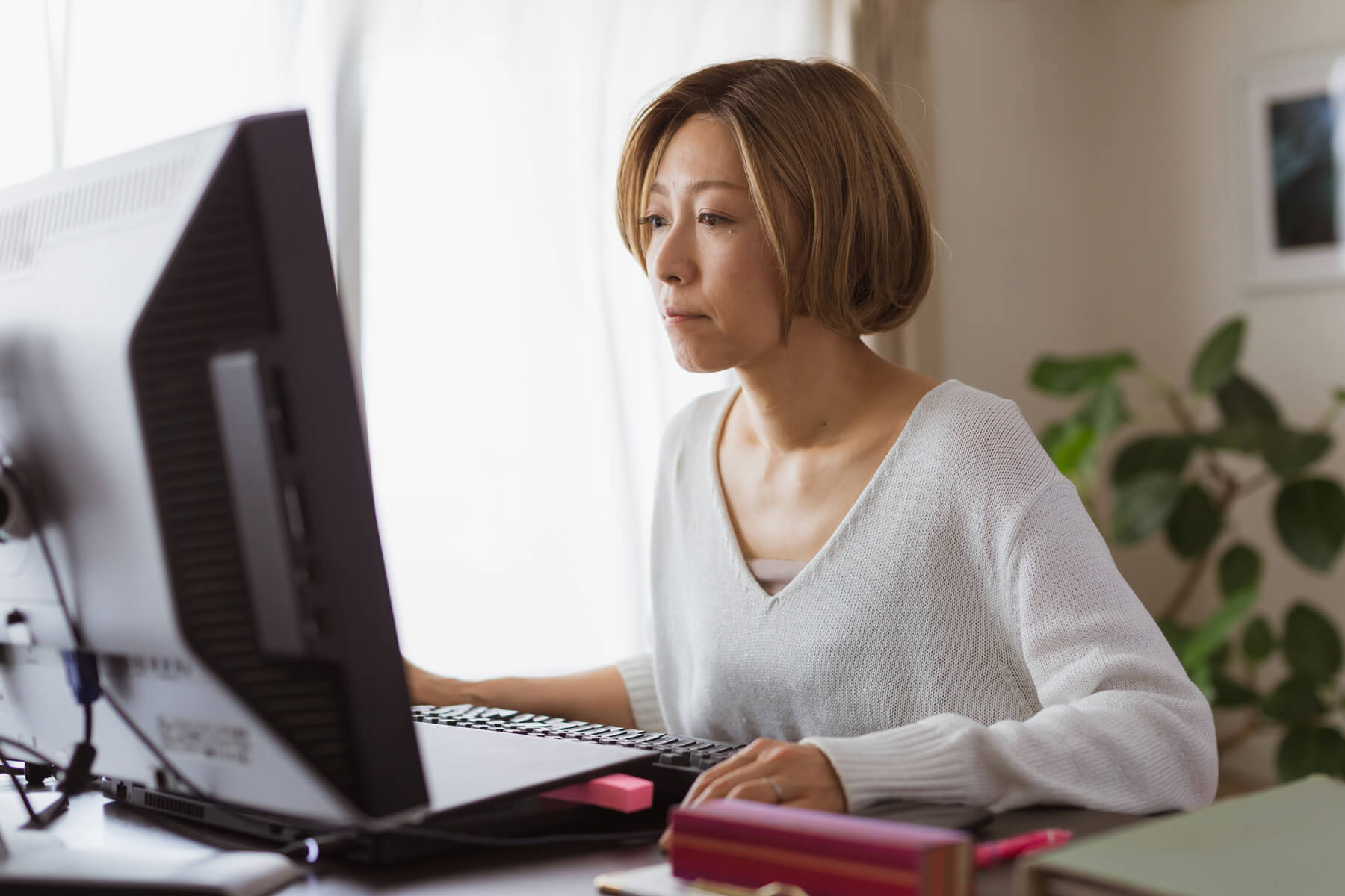 A person sits at their computer at home while concentrating on a task.