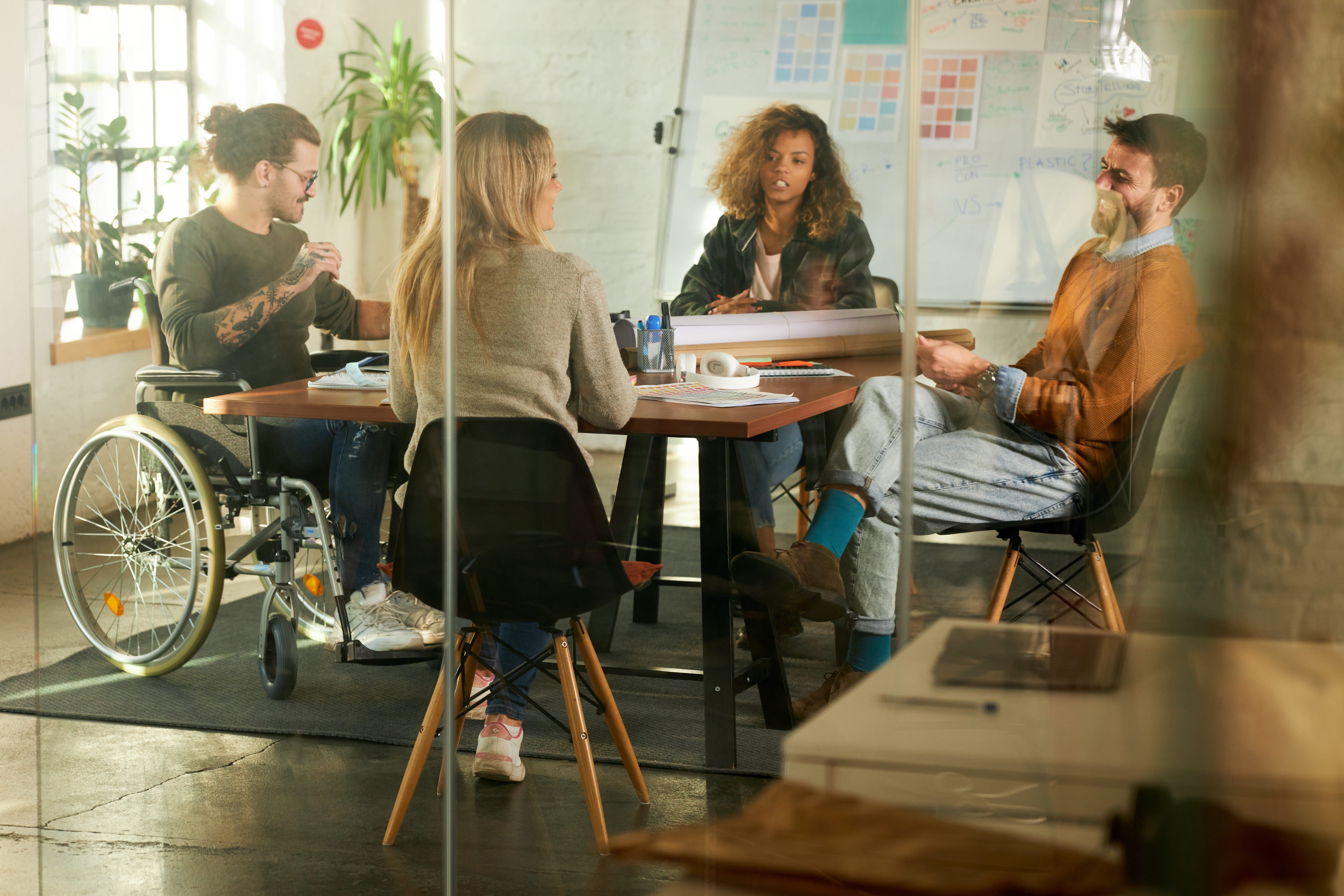 A group of colleagues discuss a project in an open plan meeting space.