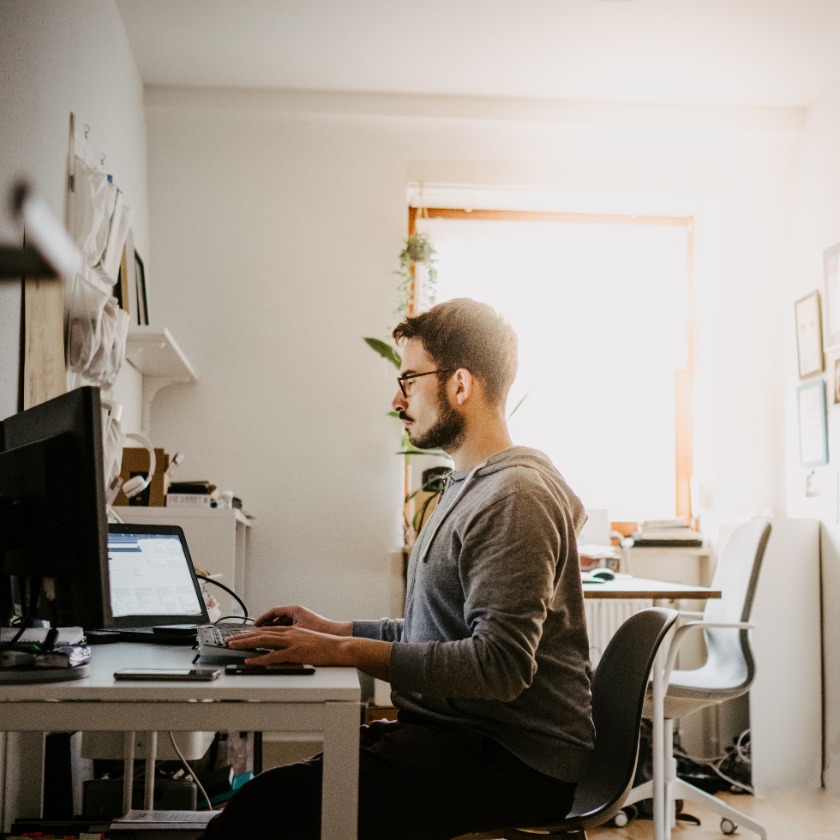 A person sits at their home office desk while concentrating on a task.