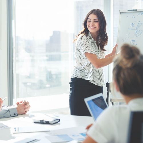 A person smiles while outlining something on a whiteboard.