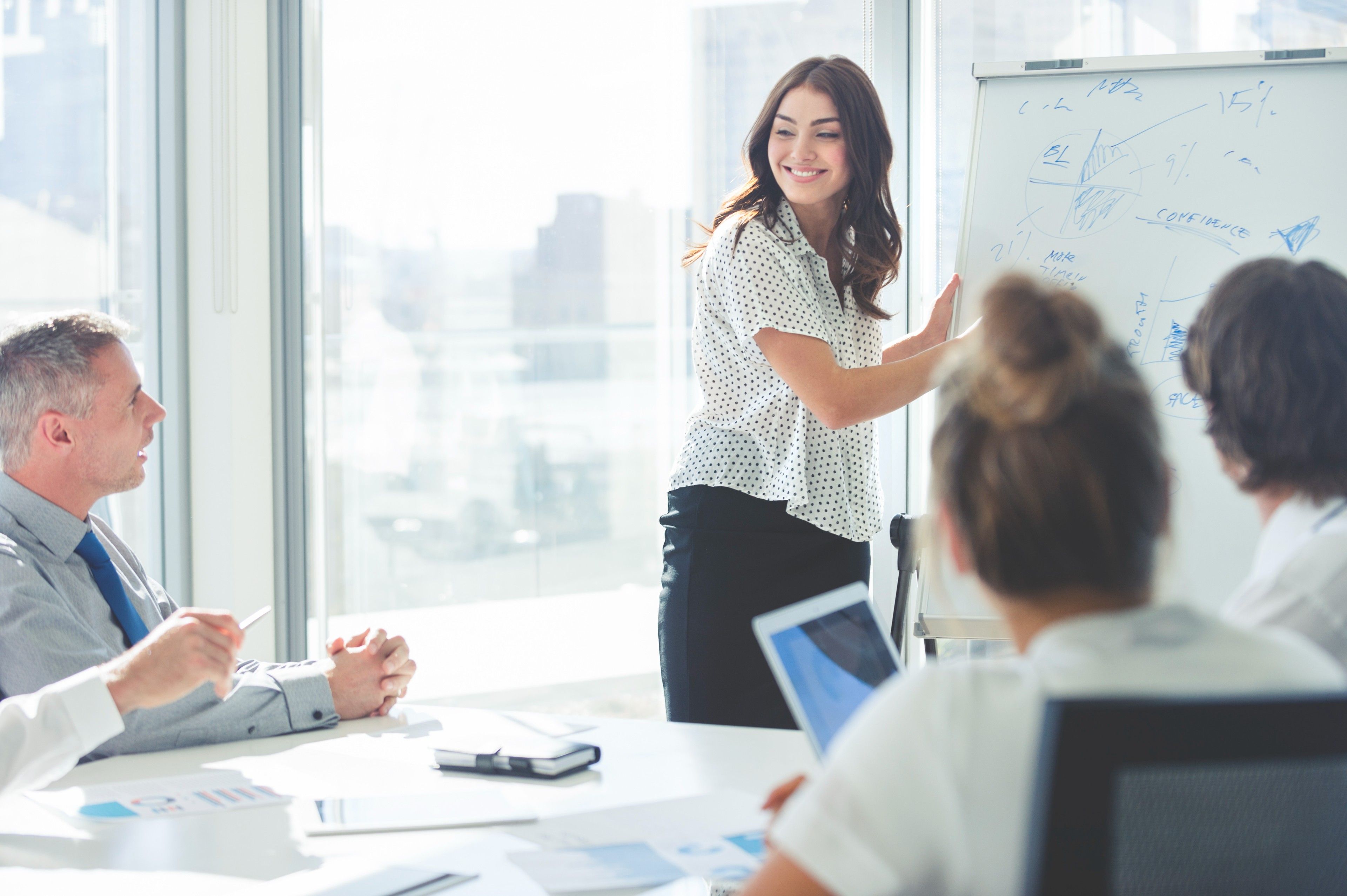 A person smiles while outlining something on a whiteboard.