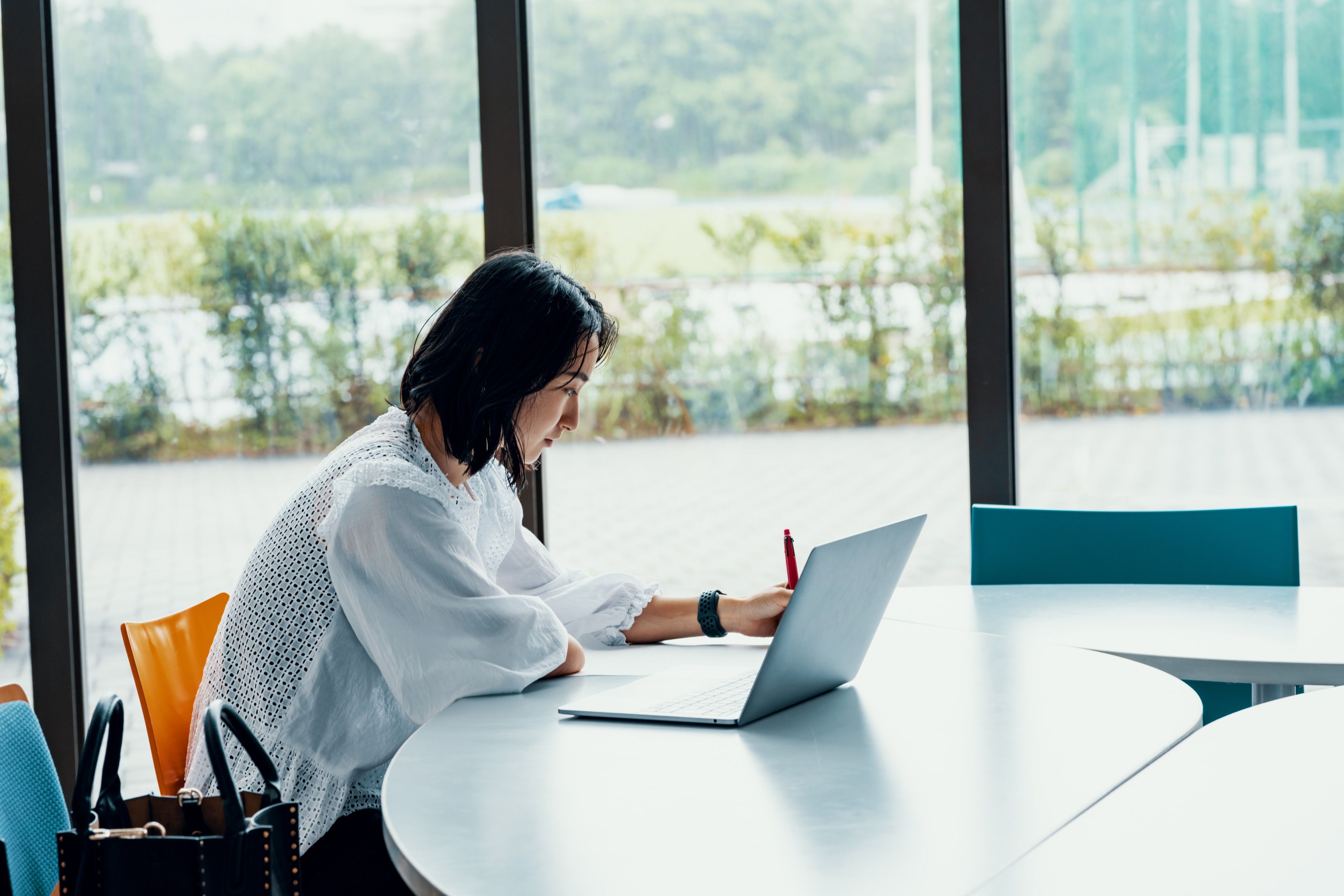 A person sits in a breakout area while making notes on their laptop.