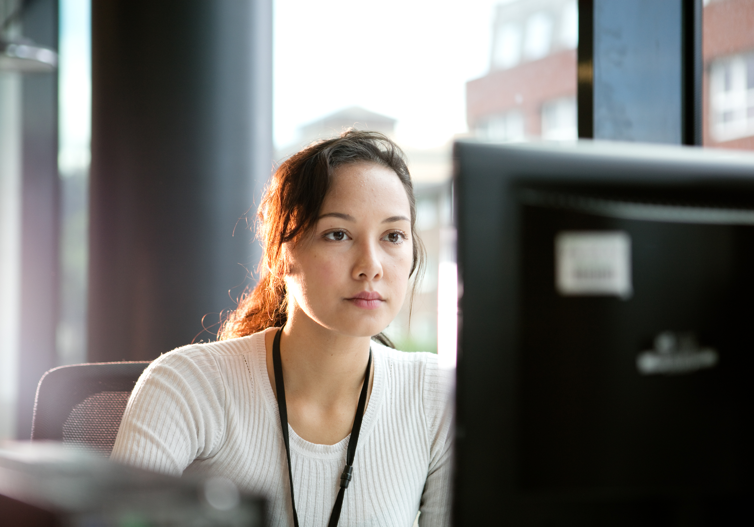 Focused professional working on a desktop computer in a bright modern office.