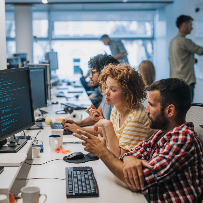 Team collaborating at computers in a modern office, discussing code and project details