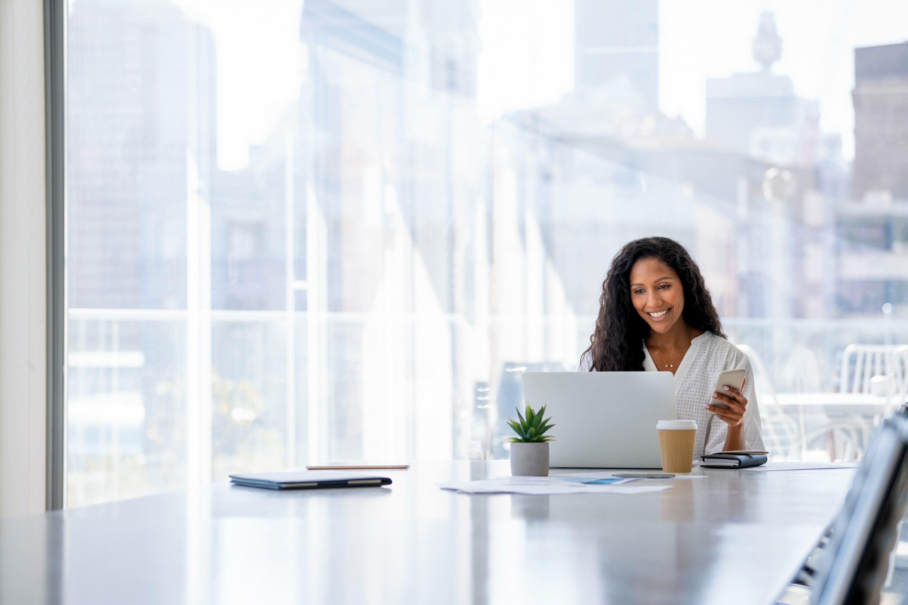 Modern workspace with a person using a laptop and mobile phone.