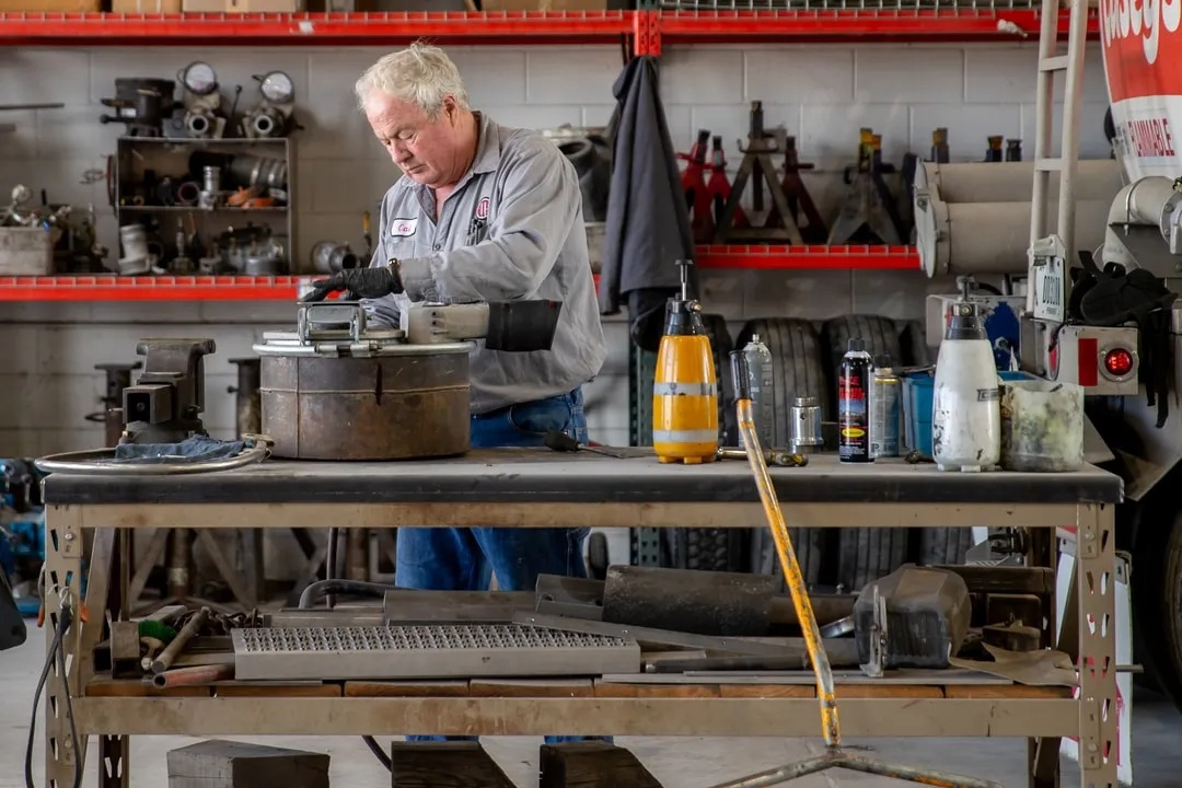 Technician inspecting exposed air-brake components and brake drum on a semi tractor in an Omaha heavy-truck service bay.