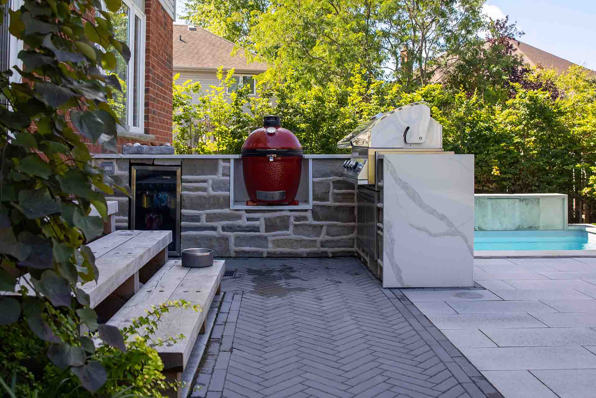 Resort-style backyard featuring a stone outdoor kitchen, pool, timber pergola, and professional putting green.