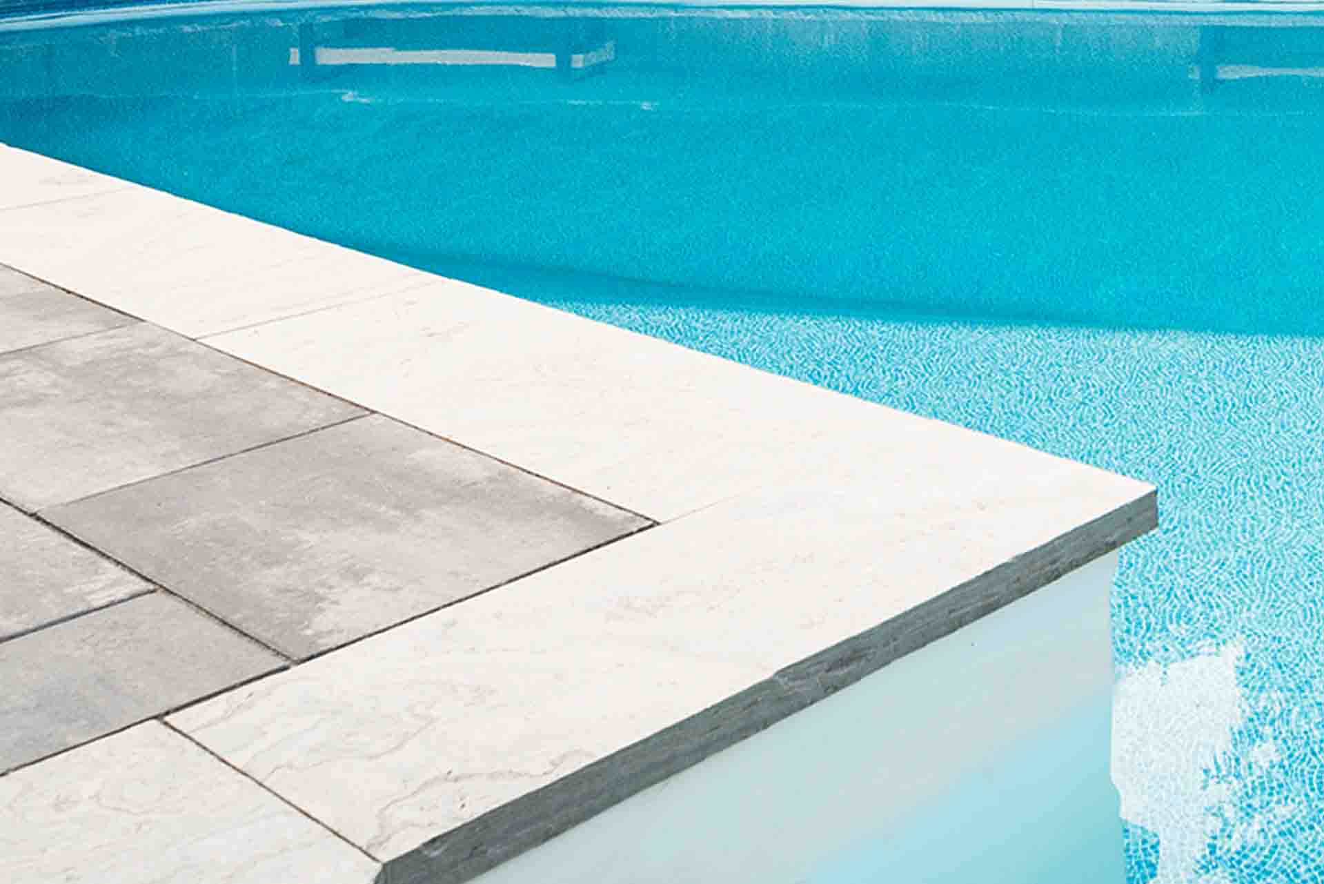Modern in-ground swimming pool with surrounding stone patio.