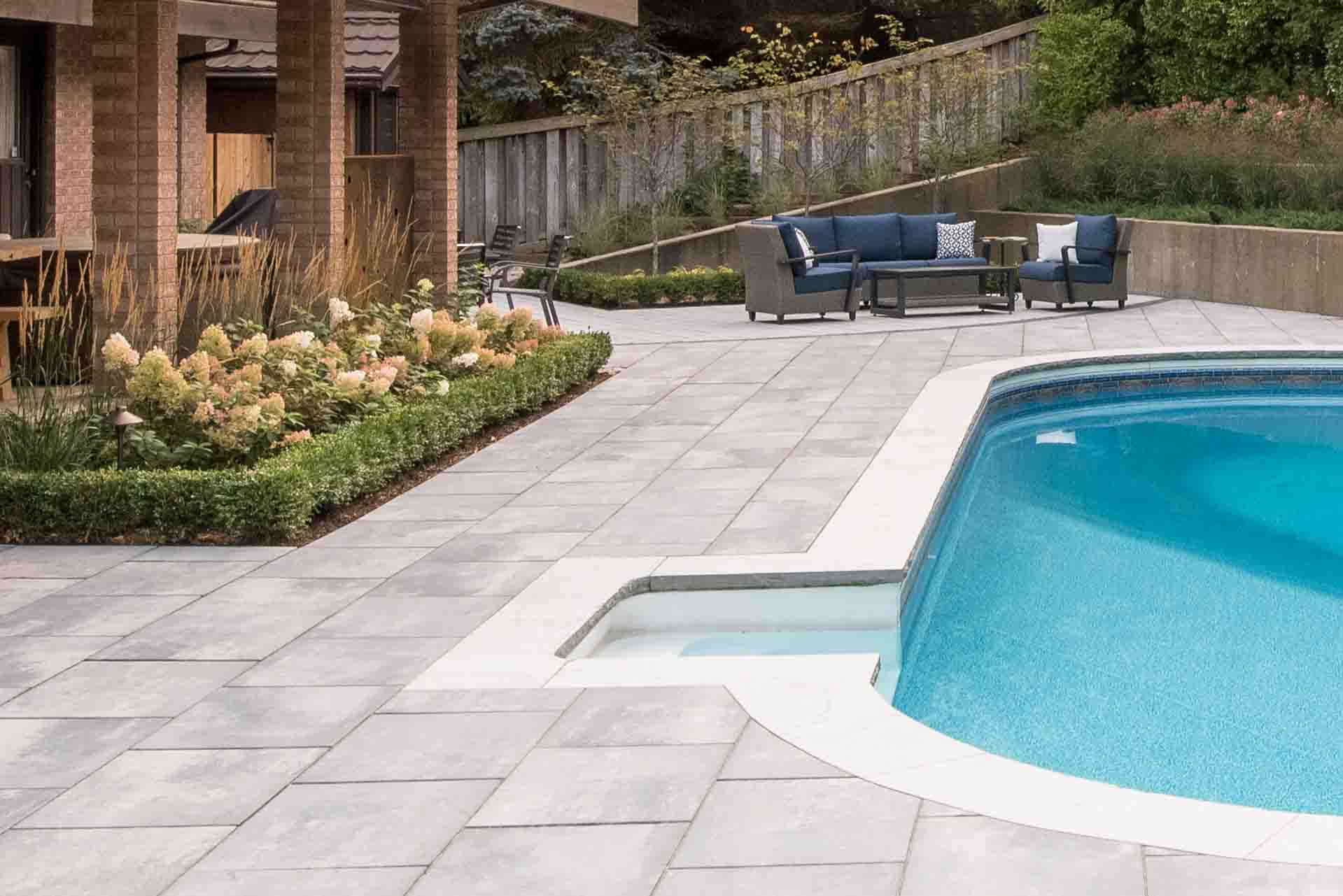 Modern in-ground swimming pool with surrounding stone patio.