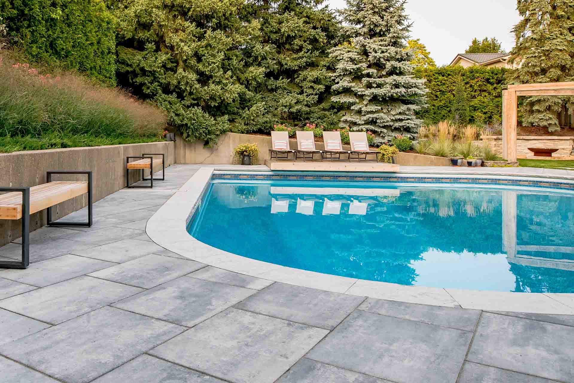 Modern in-ground swimming pool with surrounding stone patio.
