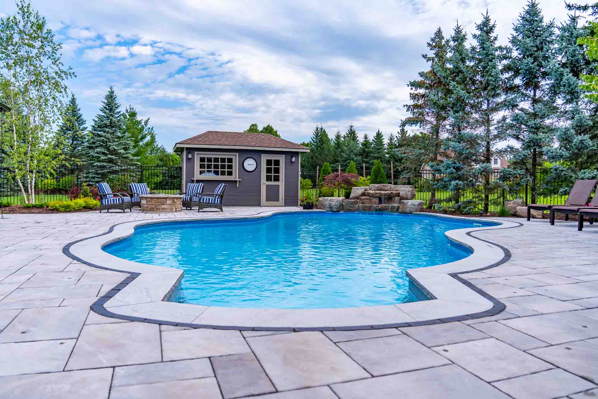 In-ground pool framed by professional landscape and patio design.