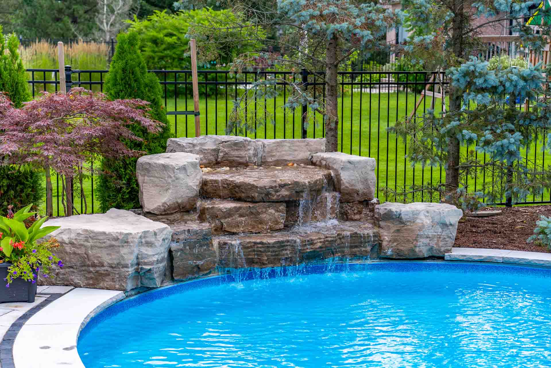 In-ground pool framed by professional landscape and patio design.