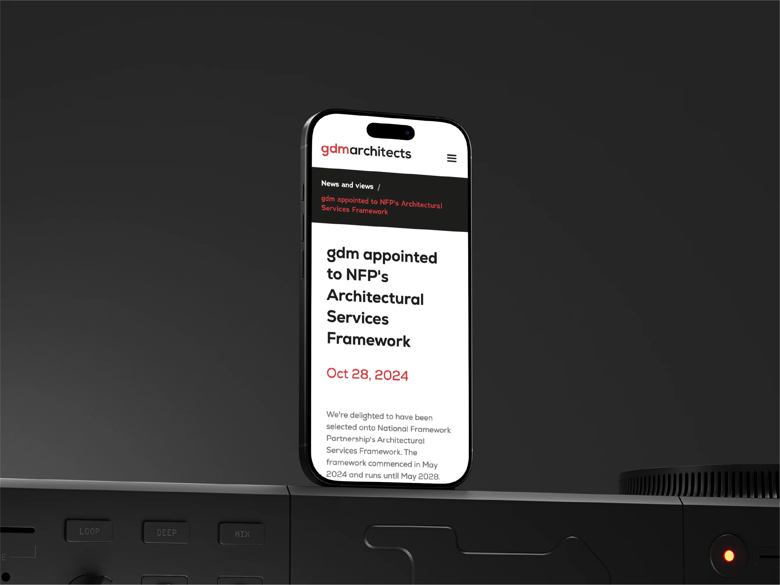 Smartphone displaying a webpage titled 'gdm appointed to NFP's Architectural Services Framework' dated Oct 28, 2024, on a dark background with a black electronic device.